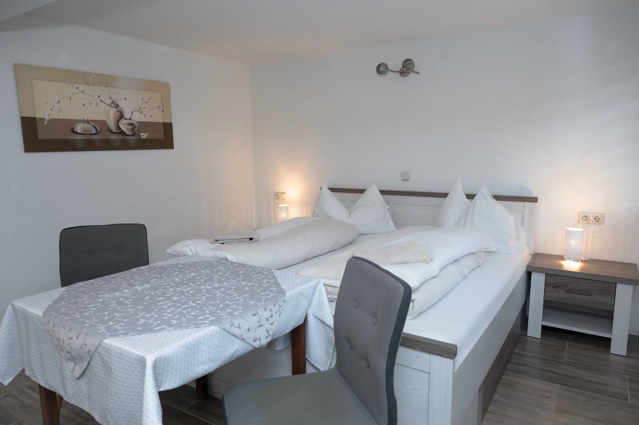 Zimmer mit Esstisch, Stühlen und Doppelbett